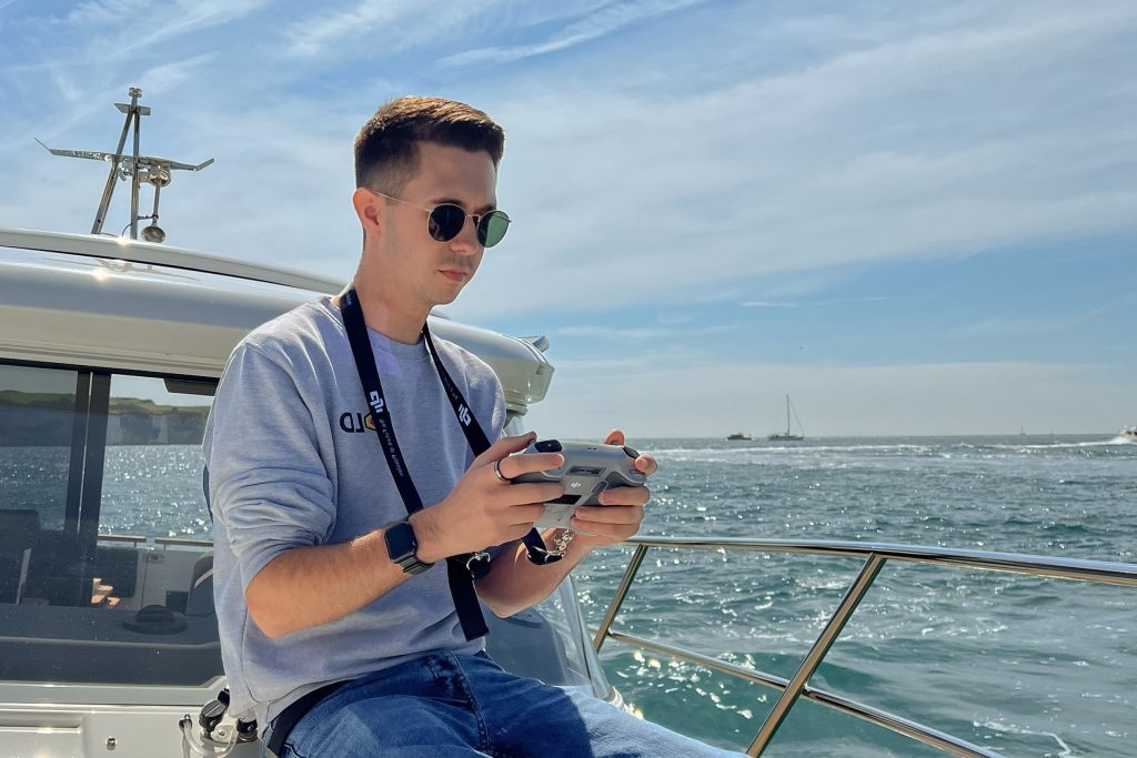 Male operating drone controller from upon a boat