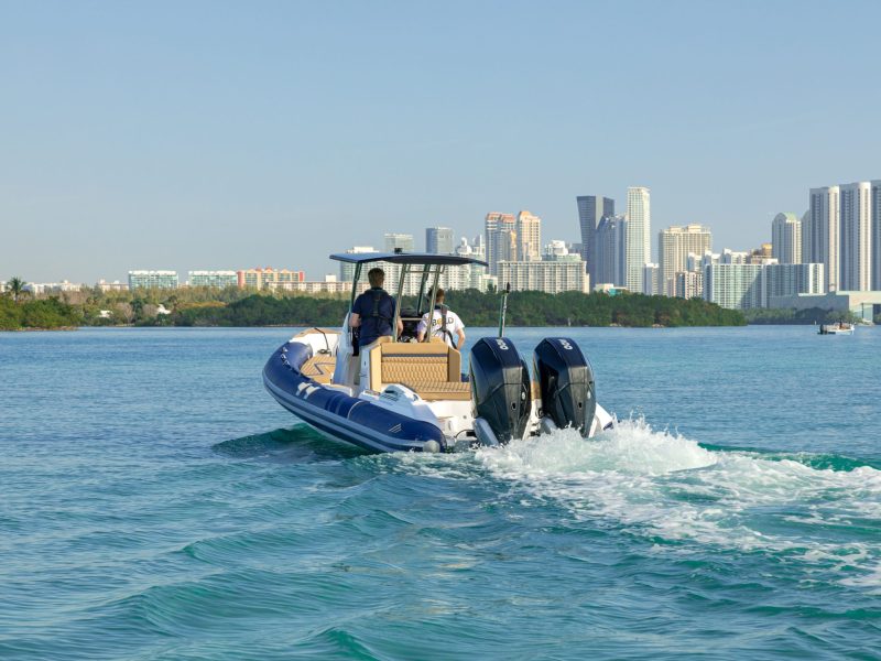 Boat travelling on water with large cityscape in the background