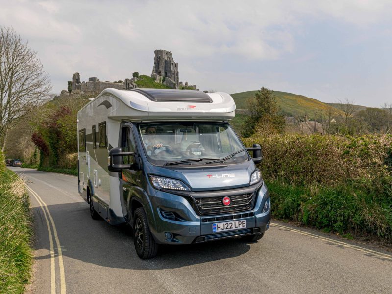 Campervan travelling on road by castle ruins