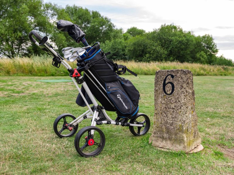 Golf trolley beside hole marker
