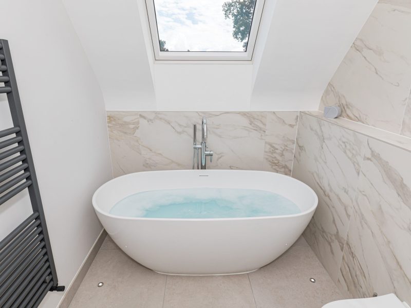 Free standing bath filling with water and bubbles in luxury bathroom